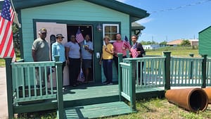 People standing in front of a restored shotgun house